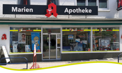 Außenansicht der Marien Apotheke in Heinsberg. Zu sehen ist der Schriftzug über der Apotheke, die Schaufenster und der Eingang. Das Bild wird mit einer dünnen grünen Welle abgeschlossen.